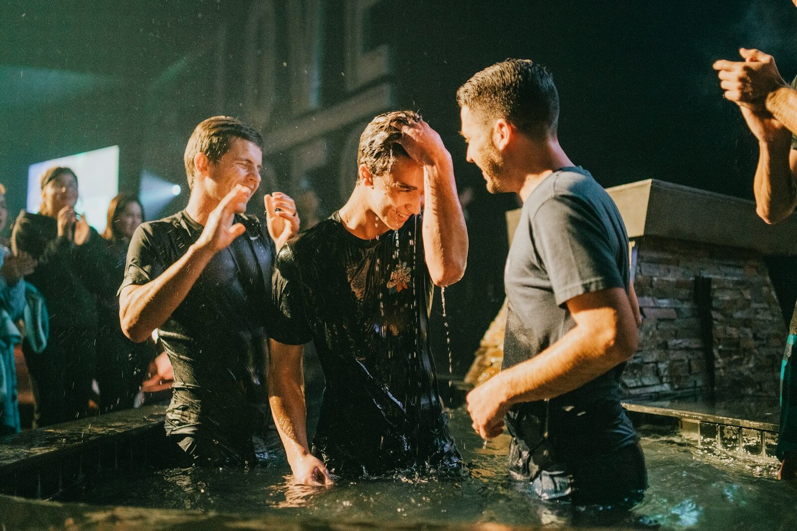 three men standing on black tub full of water
